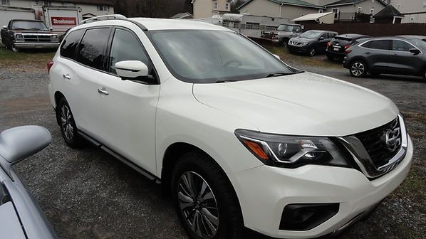 White SUV parked on a wet dealership lot, front-left view