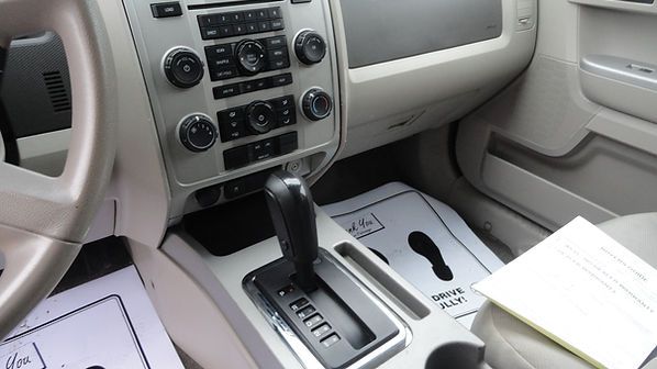 Car interior with center console, gear shifter, dashboard controls, and papers on the seats