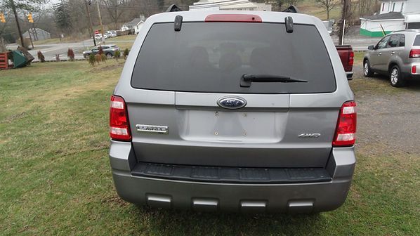 Rear view of a gray Ford SUV parked on grass on an overcast day