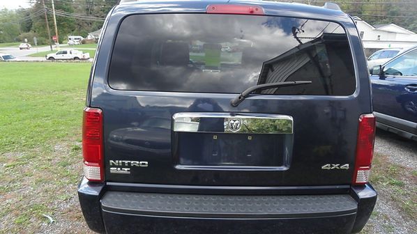 Rear view of a dark blue SUV with a broken rear window and visible damage.