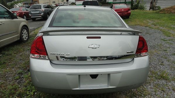 Rear view of a silver Chevrolet sedan parked in a lot, with other cars nearby.