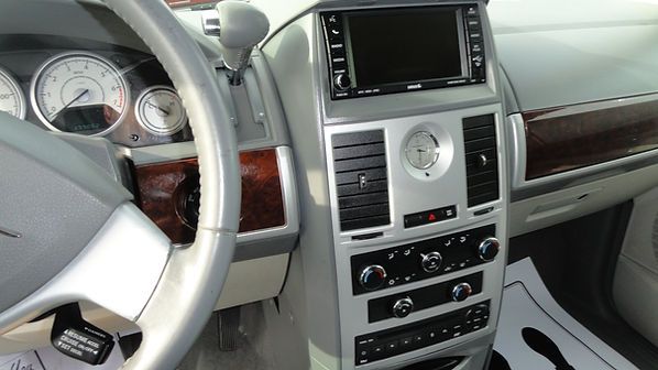 Car interior dashboard with steering wheel, center console, and wood trim in silver and beige.