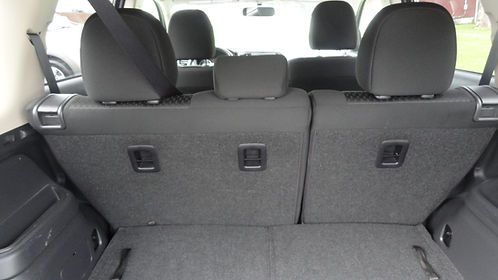 Back seat of a car with gray fabric upholstery and three headrests, viewed from the trunk area