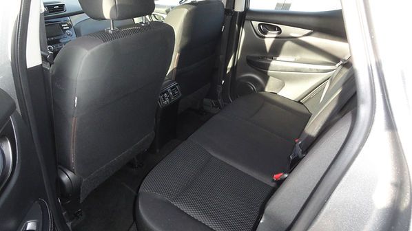 Rear car seat interior with black fabric seats and silver door trim in daylight