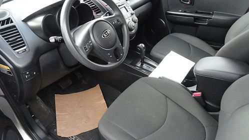 Car interior with black seats, steering wheel, center console, and a paper on the passenger seat