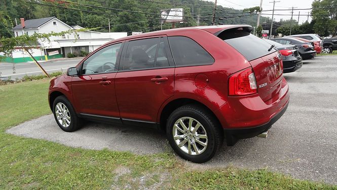 Red SUV parked on a grassy lot beside other vehicles on an overcast day