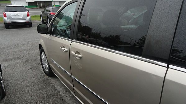 Beige minivan parked in a lot, viewed from the side near its front door.