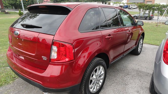 Red SUV parked in a lot, rear three-quarter view, with a silver car beside it.