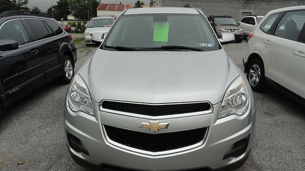 Silver Chevrolet SUV parked in a lot, front view with a green paper on the windshield.