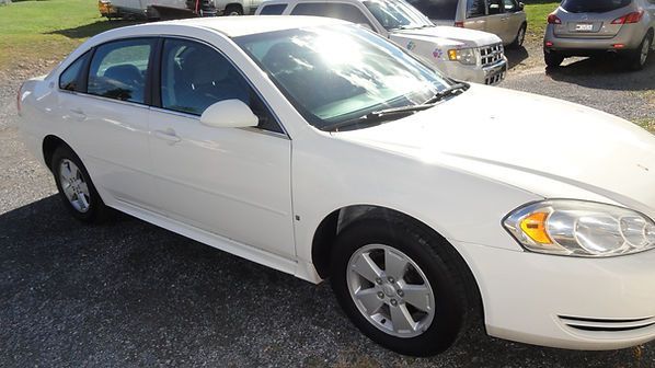 White sedan parked in a sunny lot, front-right view