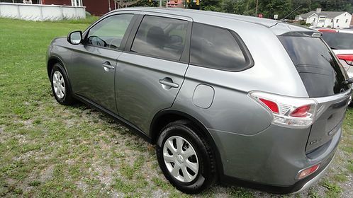 Gray crossover SUV parked on grass, side view with red taillights and tinted windows.