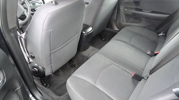 Rear seats and back of front seats in a gray car interior with black floor mats