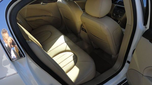 Tan leather car back seat with sunlight streaming in through the open door