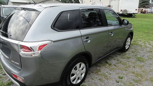 Gray SUV parked on gravel near a grassy yard and buildings