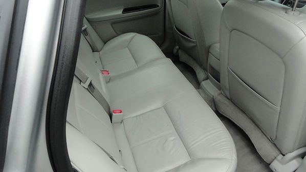 Gray leather rear car seats with red seatbelt buckles and folded armrest.
