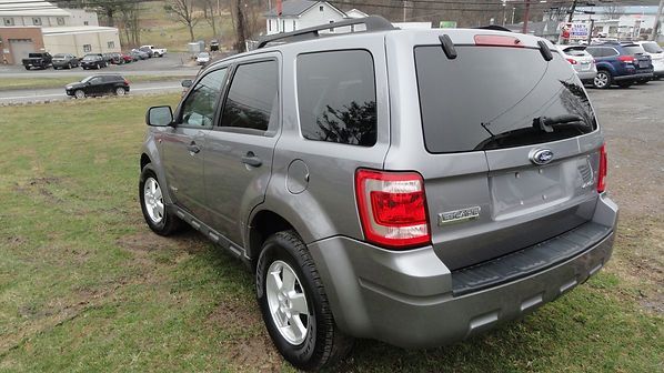 Gray SUV parked on grass near a building, rear three-quarter view