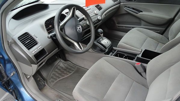 Gray car interior with steering wheel, front seats, manual gear shift, and dashboard.