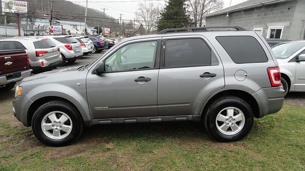 Silver SUV parked on grass beside a row of cars in a parking lot