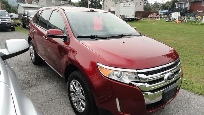Red SUV parked on a wet road in a grassy lot with other vehicles in the background