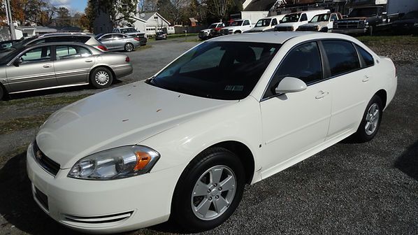White four-door sedan parked in a lot, viewed from the front-left side.