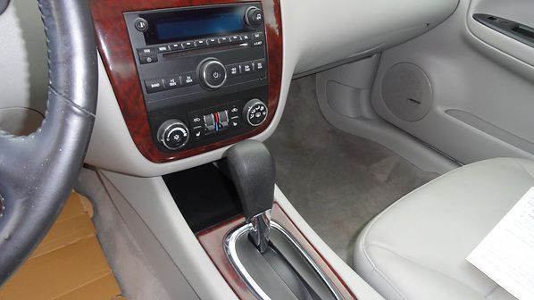 Car interior with beige seats, center console, radio, and automatic gear shift.