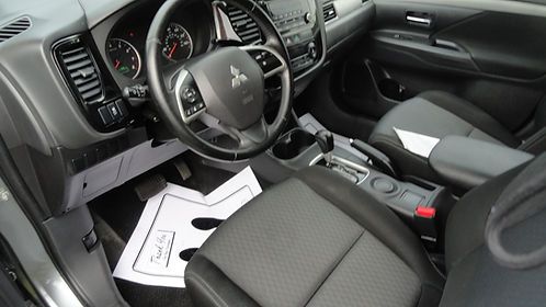 Car interior with steering wheel, front seats, and papers scattered on the passenger seat and floor.