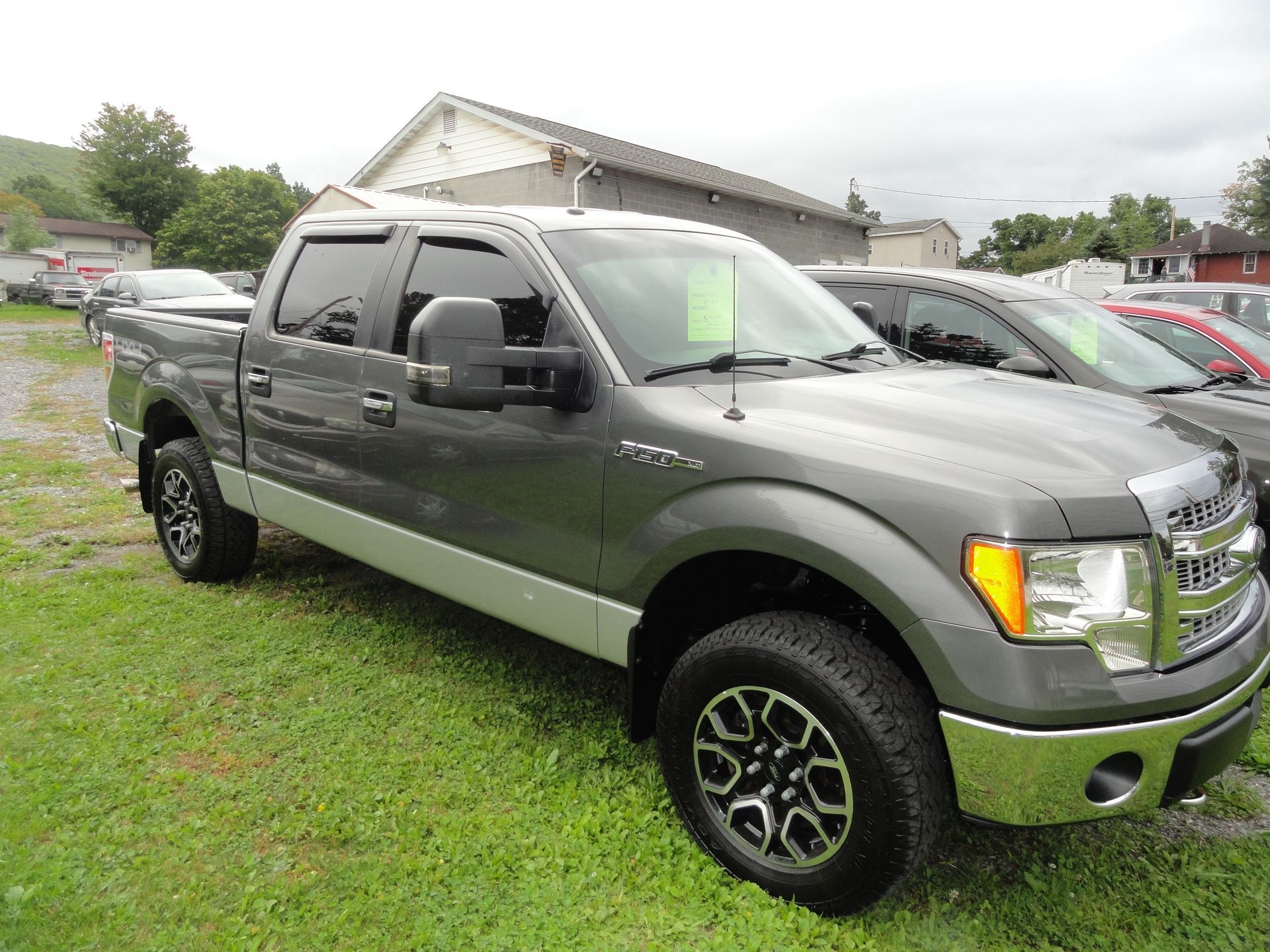 Gray and silver pickup truck parked on grass at a car lot