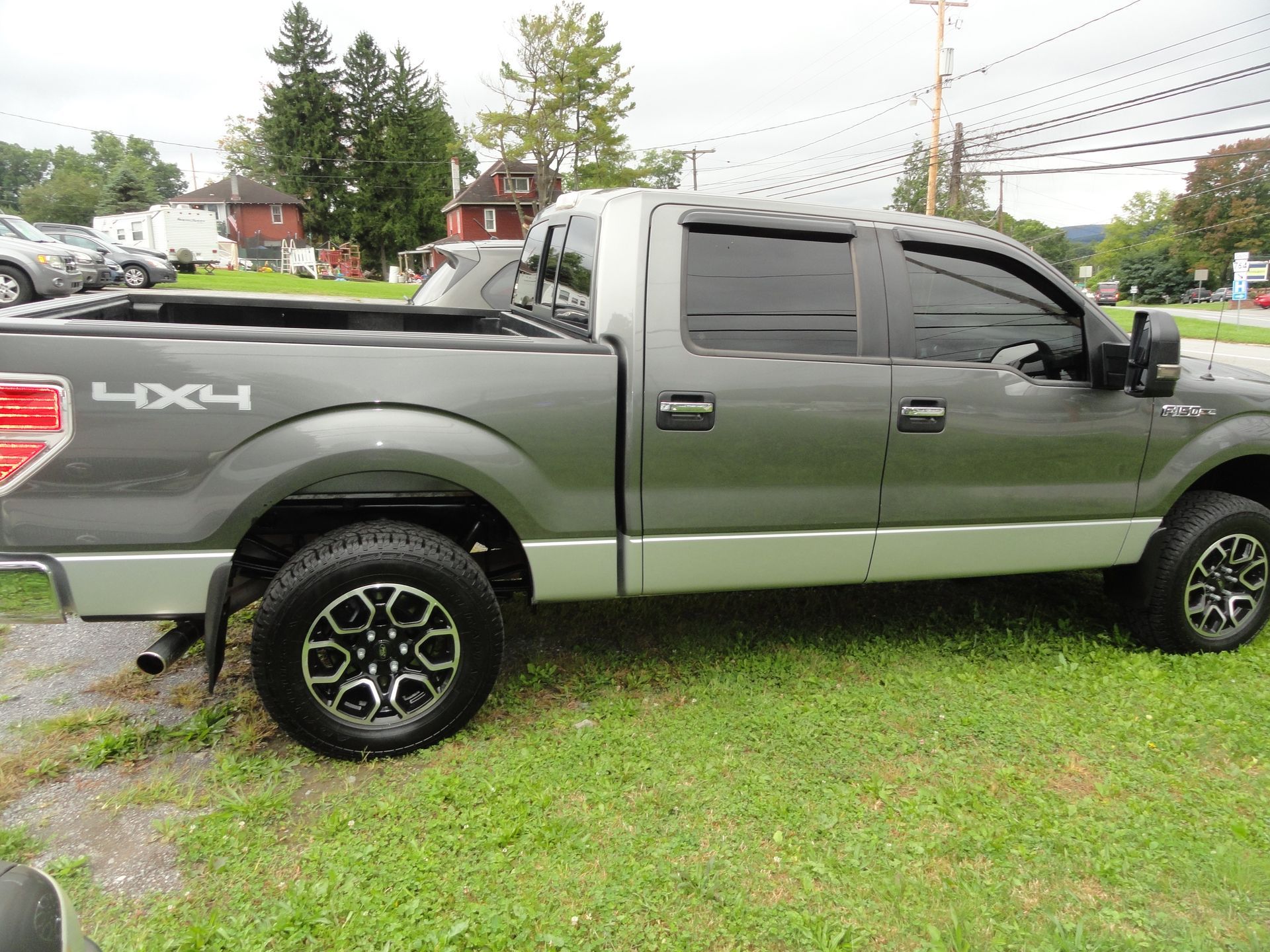 Green lifted 4x4 pickup truck parked on grass in a residential yard