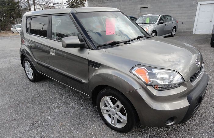 Gray compact SUV parked on gravel lot, with a red sign in the windshield.