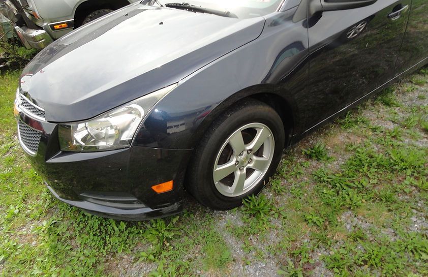 Dark blue sedan parked on wet grass, front-left view
