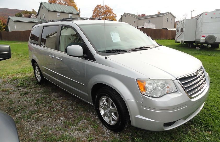 Silver minivan parked on a grassy lot in a suburban neighborhood