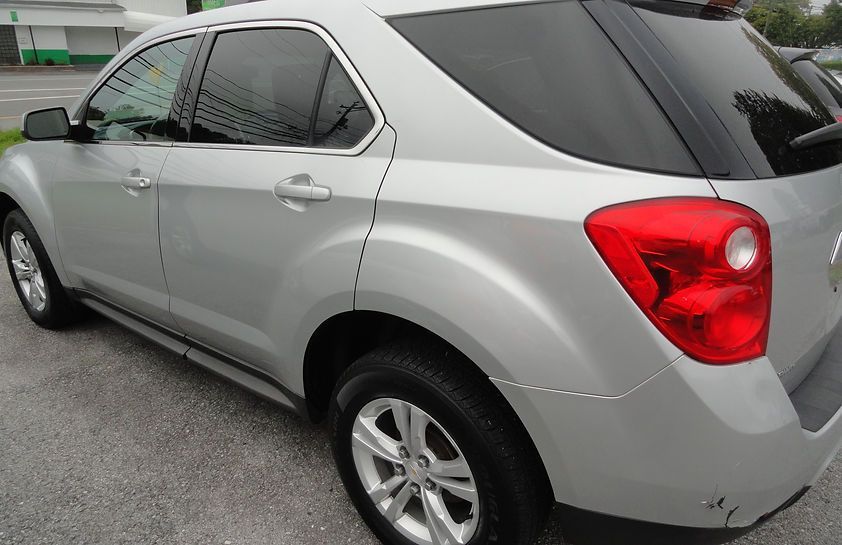 Silver SUV parked on a street, rear side view with red taillight visible