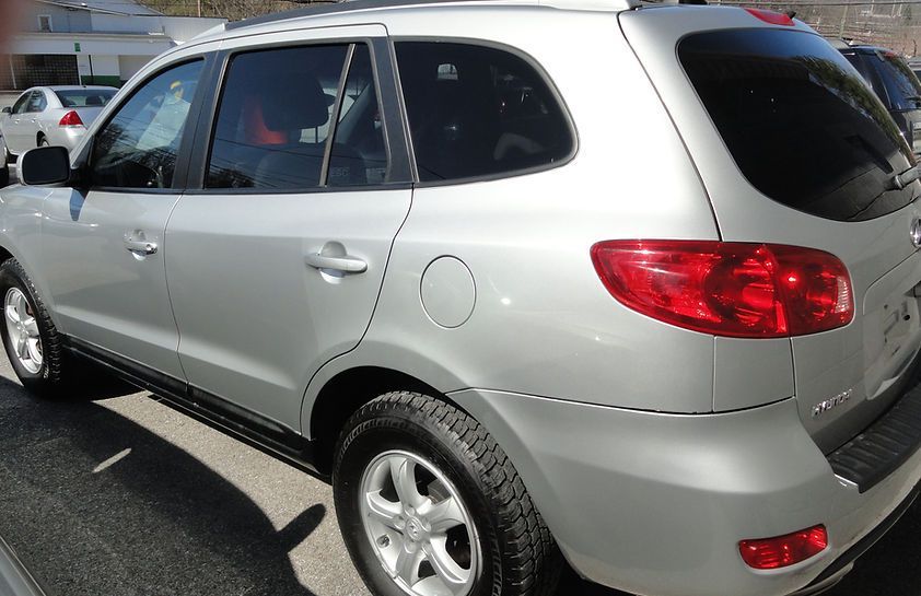 Silver SUV parked in a lot, rear side view with red taillights and tinted windows