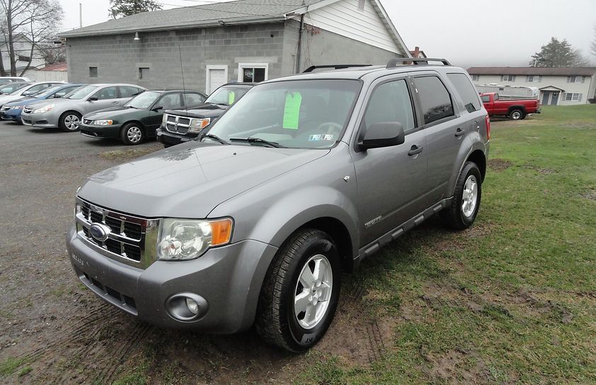 Silver SUV parked on grass in front of a building on an overcast day