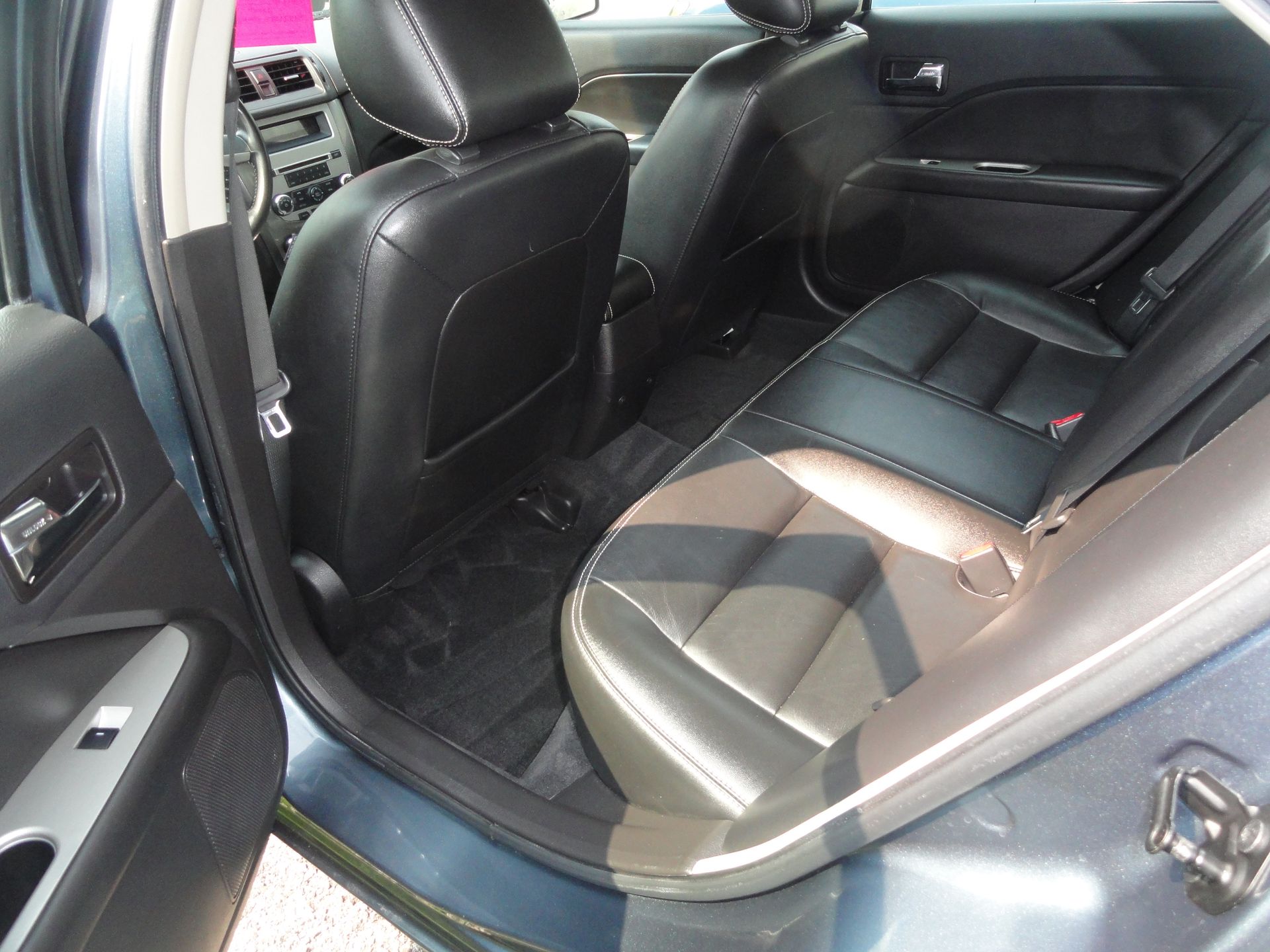 Car interior with black leather seats and an open rear passenger door