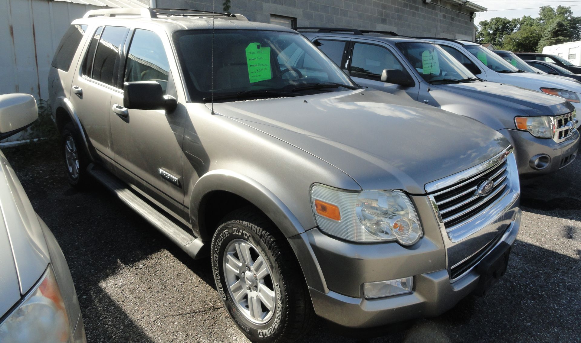 Silver SUV parked beside other vehicles at a car lot, with a green price tag on the windshield.