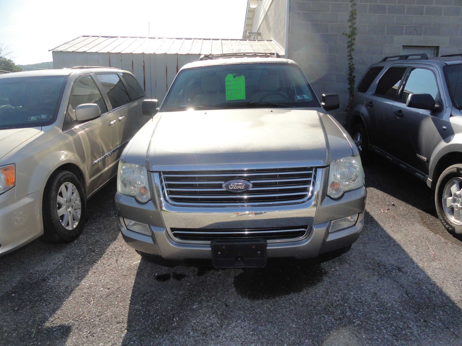 Silver SUV parked in a lot, front view, with a green sign in the windshield