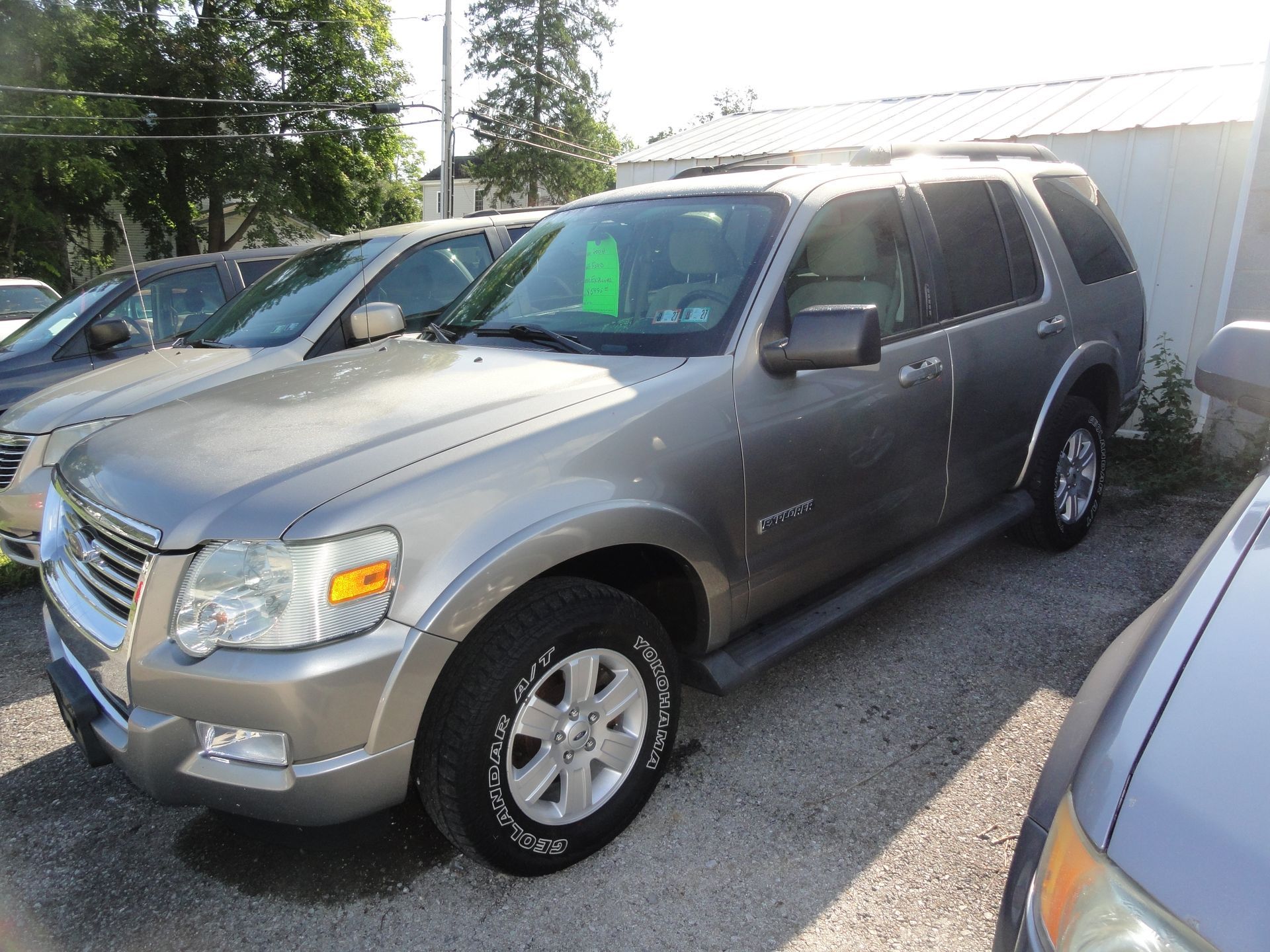Silver SUV parked in a lot beside other cars and a white fence