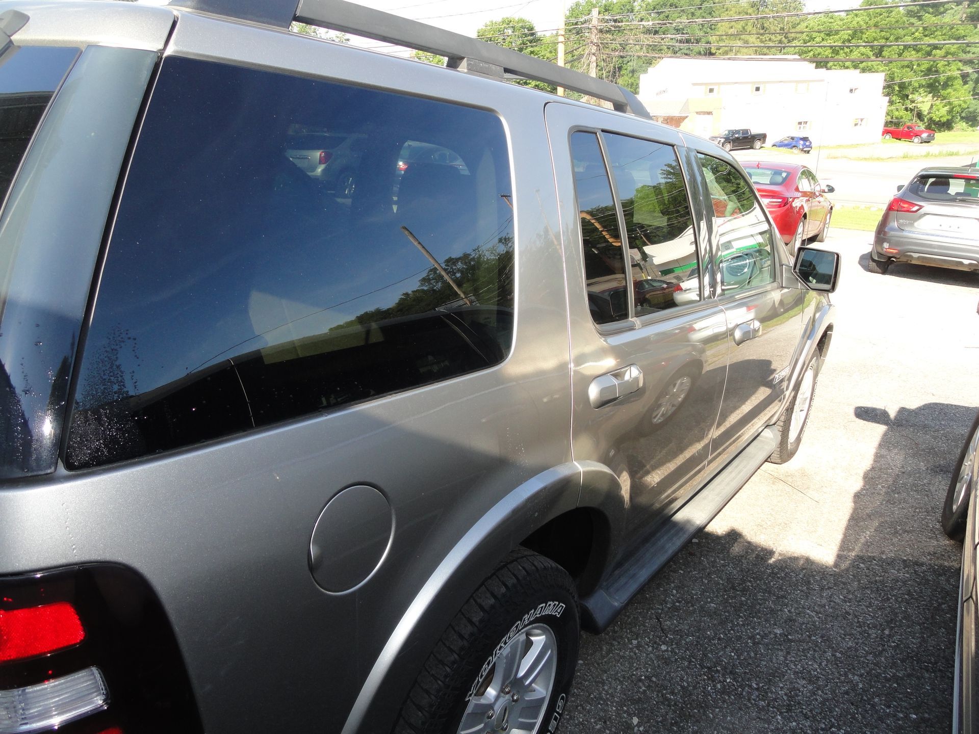 Silver SUV parked in a sunny outdoor lot, viewed from the rear side.