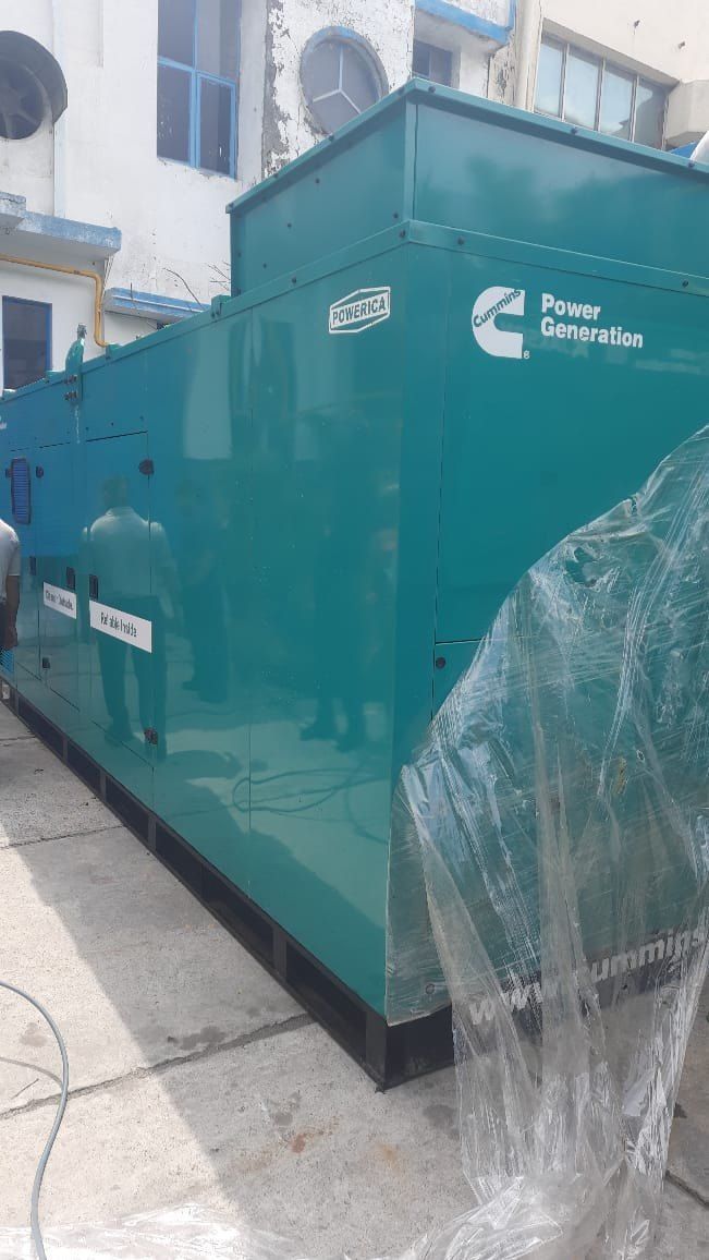 Green Cummins generator outside a building.