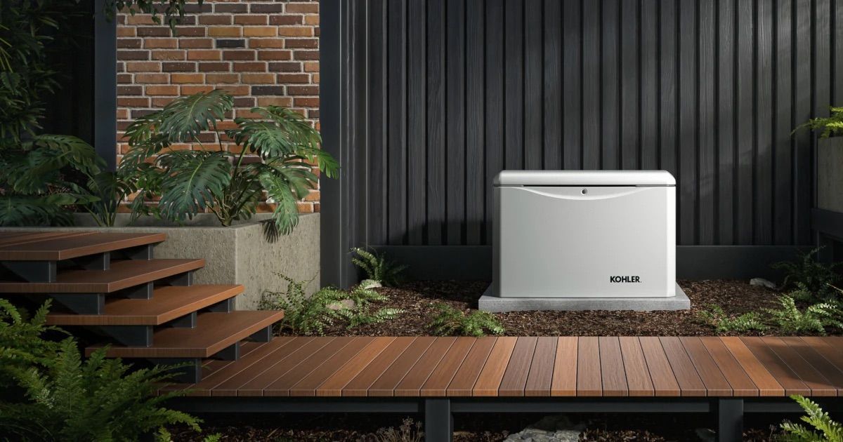 Exterior view of a white generator on a concrete pad near a wooden walkway and brick wall.