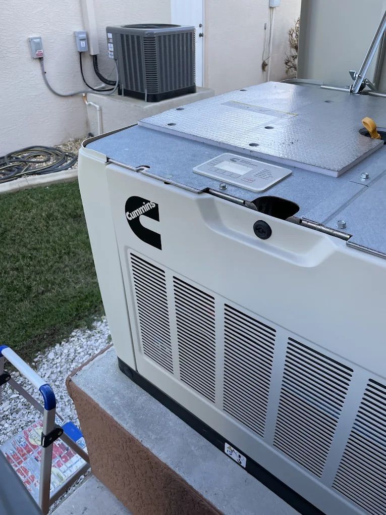 Cream-colored Cummins generator, metal roof panels, next to an AC unit, on a concrete pad.