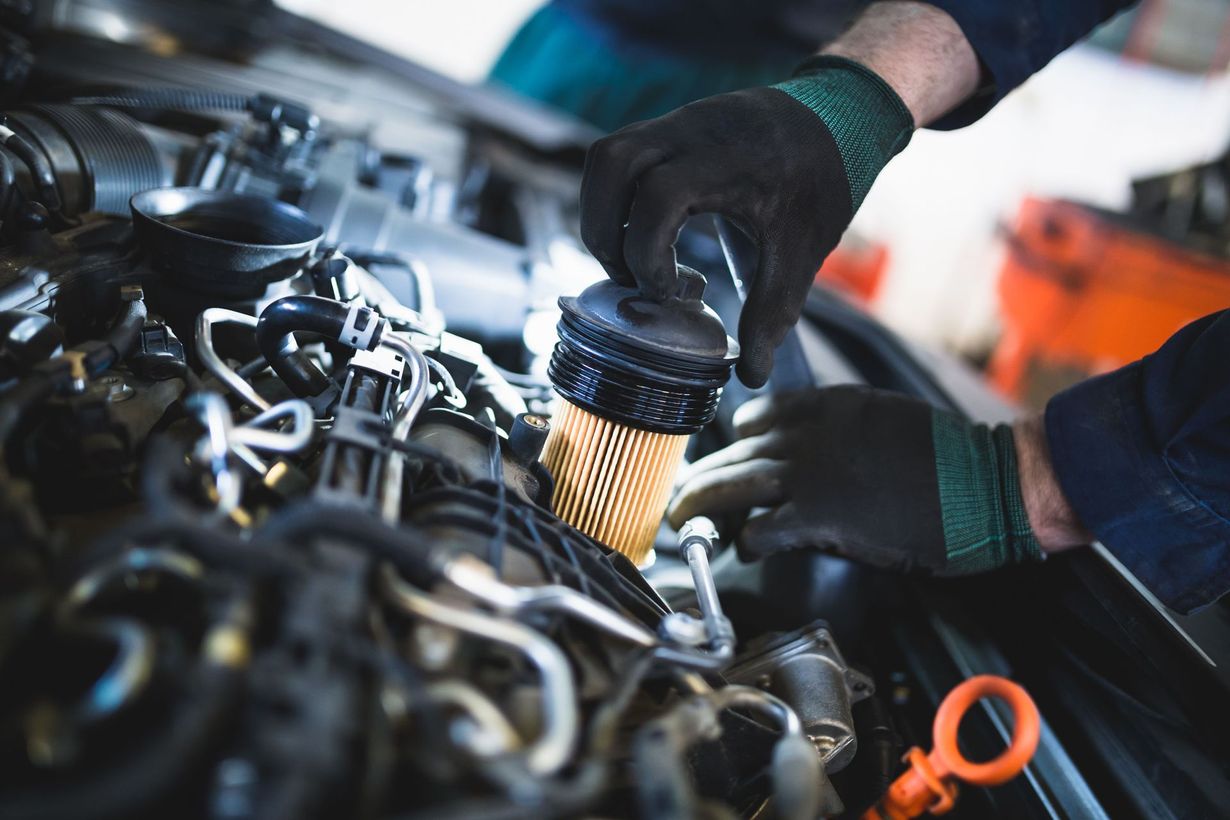 Mechanic using a tool to remove a car air filter in an engine bay
