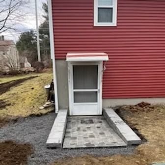 Red house with white door and ramp entrance.