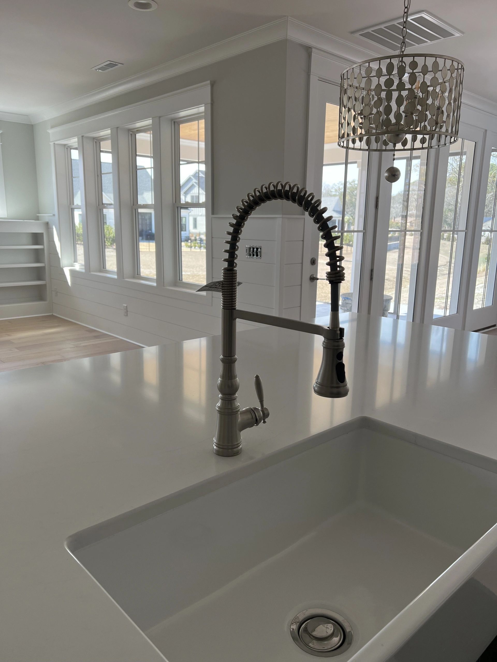 A kitchen sink with a faucet and a chandelier hanging from the ceiling.