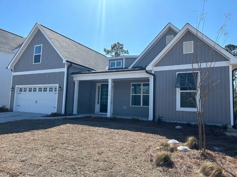 A gray house with a white garage door and a porch.