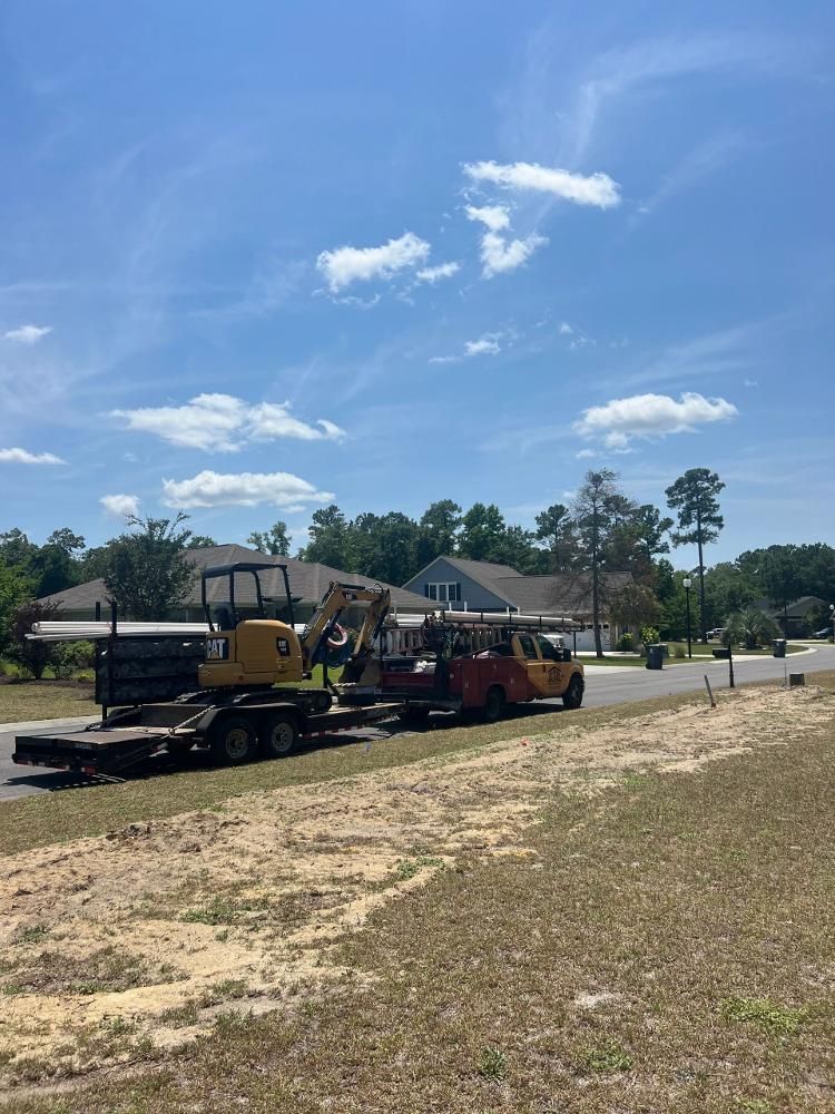 A truck is towing a bulldozer down a dirt road.