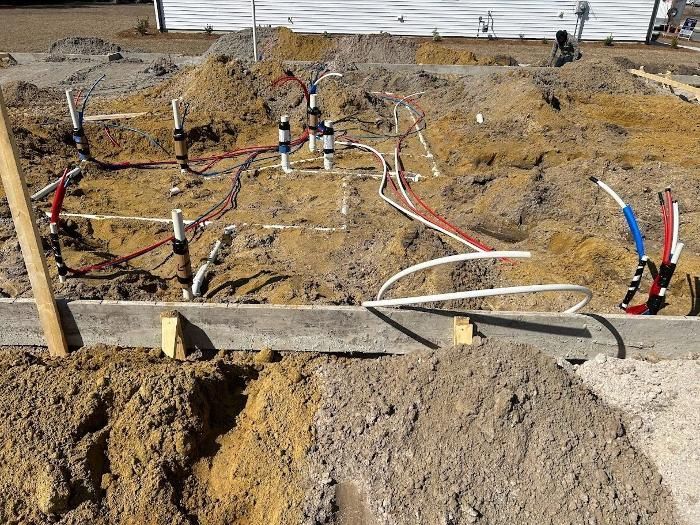 A bunch of wires are laying in the dirt on a construction site.