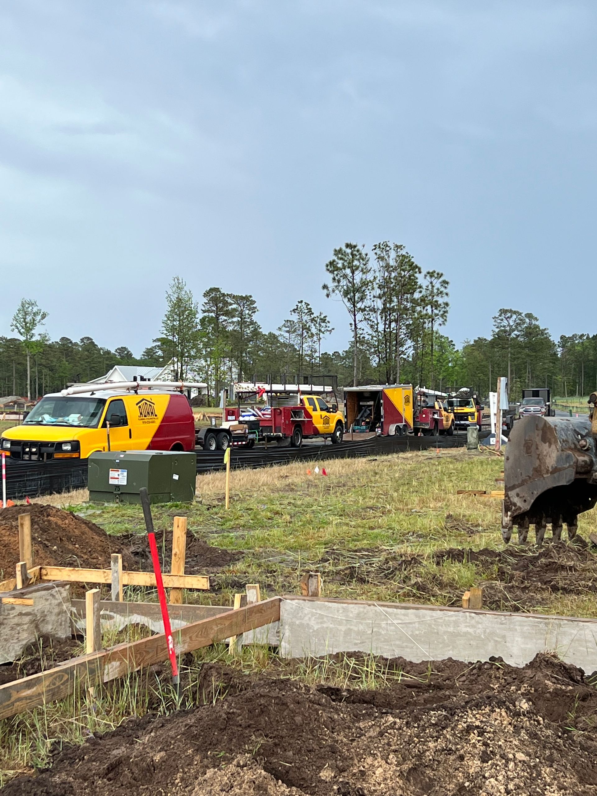 A bunch of construction trucks are parked in a field.