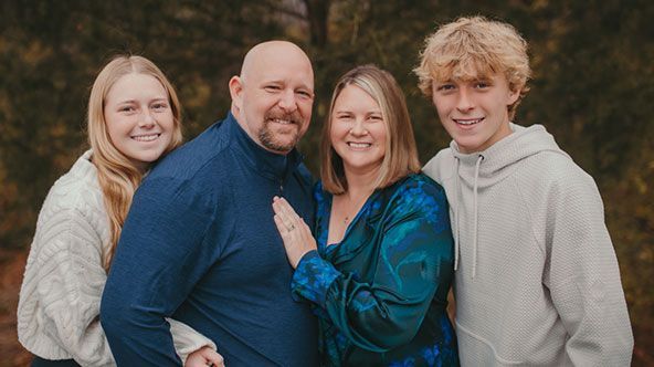 A family is posing for a picture together in the woods.